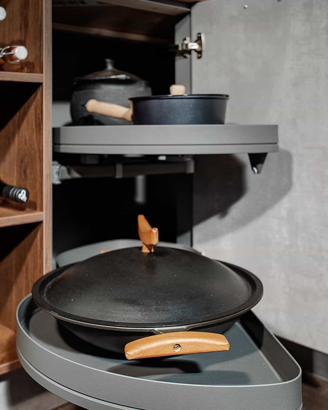 Rangement intelligent d’angle coulissant pour cuisine sur mesure avec plateaux pivotants, casseroles et poêles intégrées dans un meuble design